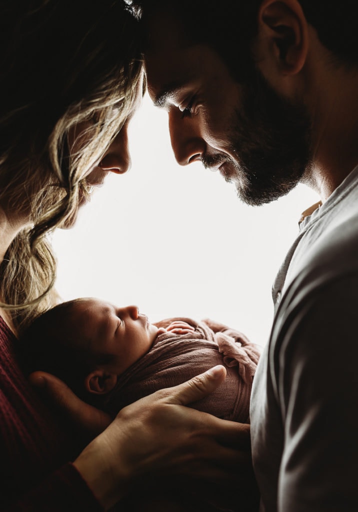 Newborn Photographer, Mother and father hold and admire their new baby
